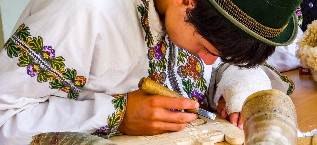 Junger Mann in Tracht beim Schnitzen